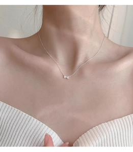 Close-up of minimalist 925 silver bow pendant necklace with crystals on woman neck
