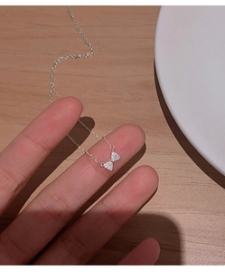 Close-up of sparkling bow pendant necklace with micro-paved zircons in silver finish