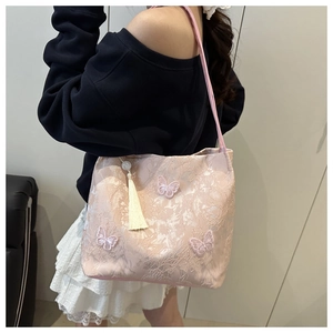 Detailed view of pink floral jacquard tote bag with 3D butterfly embroidery and fringe charm