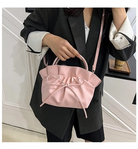 Detail of pink ruffled cloud bag with bow ornament on gray blazer outfit
