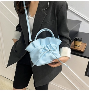 Detail of light blue pleated tote bag with bow accent and long shoulder strap