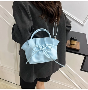 Detail of light blue pleated cloud bag with bow ornament shown in a modern interior setting