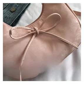 Detailopname van roze halvemaantas met strikdecoratie en getextureerd kunstleer