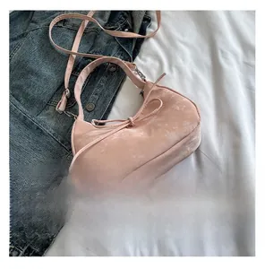 Detail van roze hobo tas met fluwelen textuur en een delicate decoratieve strik