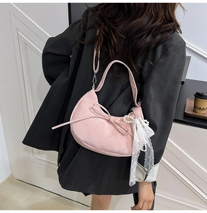 Detail van roze halvemaanvormige tas met strik en parel-kant hanger aan de zijkant