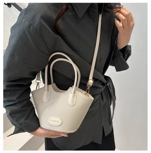 Detail of woven texture handbag featuring a fashion logo patch and adjustable strap