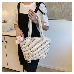 Detail of hand-woven straw tote bag with beaded tassel and natural bohemian texture