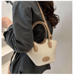 Detail of straw bucket bag with adjustable leather strap and Fashion patch on shoulder
