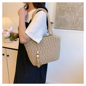 Detail of khaki woven tote bag with black polka dots and wooden bead tassel ornament