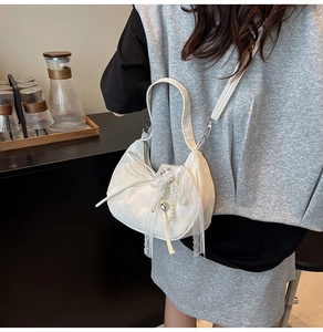 Detailweergave van witte satijnen halvemaanvormige tas met kant, parels en roze strikjes