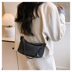 Close-up of black lychee grain leather Lindy bag featuring gold metal turn-lock closure