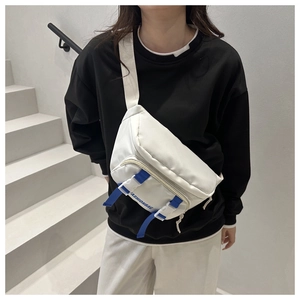 Detailed view of white nylon crossbody bag featuring blue fashion straps on model