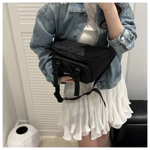 Detail of black tactical crossbody bag with dual buckles and adjustable strap on model