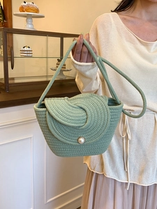 Sac seau tressé vert clair avec boucle en perle dans un décor de salon de thé français