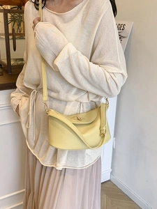 Minimalistische hellgelbe Leder-Eimertasche mit Goldbeschlägen an einem Model