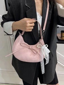 Roze halve maan tas met strik en parelhanger gedragen bij een zwarte blazer