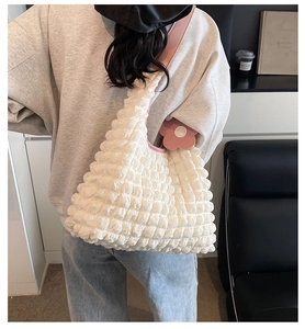 Detailed view of the bubble textured fabric and pink leather strap on this white tote bag