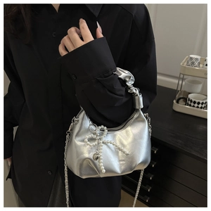 Detail of silver metallic crescent hobo bag with pearl bow charm and chain strap