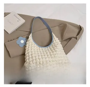 Detail of cream popcorn texture shoulder bag with blue strap and floral charm accessory
