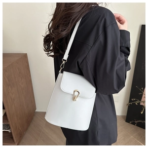 Detailed view of white leather bucket bag with gold teardrop lock on shoulder
