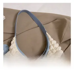 Detail of white bubble texture tote bag featuring a light blue handle and flower charm