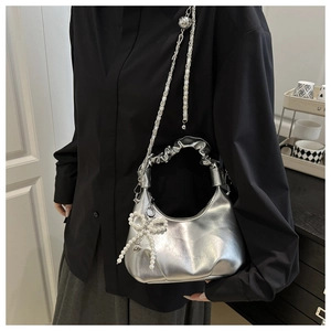 Detail of silver metallic handbag featuring cloud-pleated handle and pearl bow charm