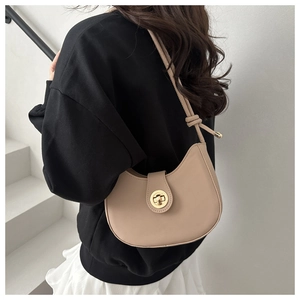 Sac demi-lune beige chic avec fermoir doré porté à l'épaule par un mannequin stylé