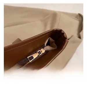 Close-up of golden metal zipper on a dark brown leather tote bag with fabric lining