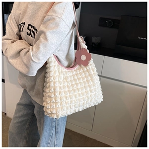 Detail of white bubble textured shoulder bag with pink leather trim and flower charm