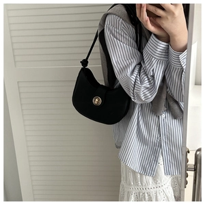 Détail du sac demi-lune noir avec boucle dorée ronde et bandoulière à nœud décoratif