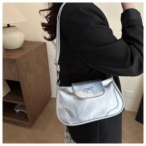 Détail du sac à bandoulière argenté avec boucle décorative en métal sur le rabat avant