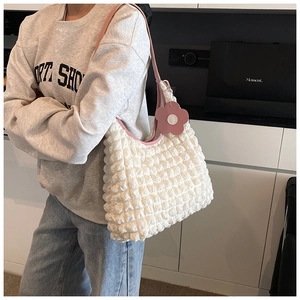 Détail du sac à bandoulière blanc texturé avec bordure en cuir rose et breloque fleur