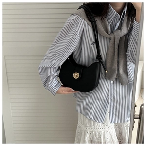 Selfie miroir montrant un sac demi-lune noir avec un fermoir rotatif doré circulaire