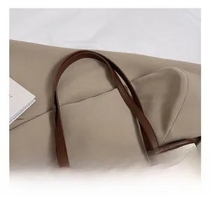 Detail of leather handle and gold rivet hardware on beige patterned tote bag