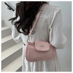 Detail of pink saddle bag featuring a silver bow buckle on smooth synthetic leather