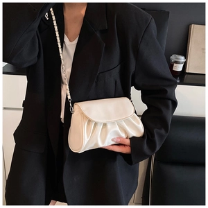 Detail of white pleated handbag with silver chain strap paired with a black blazer