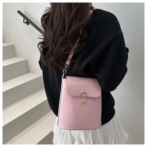 Close-up of pink leather bucket bag featuring a gold horseshoe buckle and shoulder strap