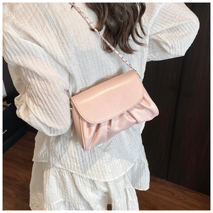 Side view of soft light pink pleated crossbody bag with metal chain strap worn by model