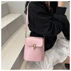 Close-up of pink bucket bag with gold horseshoe clasp worn over a white pleated skirt