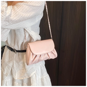 Detailed view of light pink cloud bag with ruched texture and woven chain strap