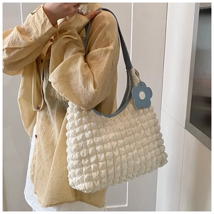 Detail of white textured bubble bag with navy blue shoulder strap and flower charm