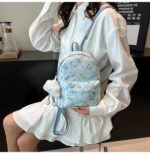 Gros plan d'un mini sac à dos floral bleu clair avec poche zippée et breloque nuage en peluche