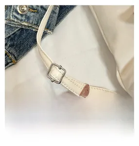 Detail of adjustable metal buckle and stitching on white leather shoulder bag strap