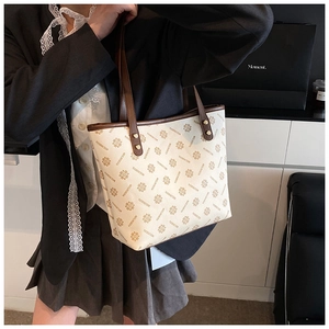 Detail of vintage tote bag with floral print and brown straps on a model in a blazer