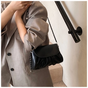 Detail of soft pleated black cloud shoulder bag with silver chain strap on model