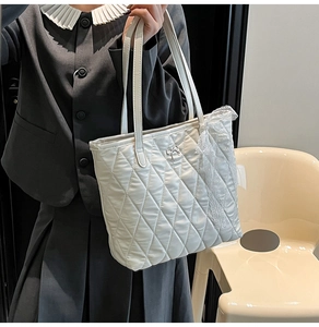 Détail du sac cabas matelassé blanc avec bordure en dentelle et nœud argenté