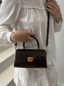 Deep brown oil wax leather crossbody bag with golden buckle and circular top handle