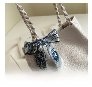 Detail of cream woven leather tote bag featuring a decorative blue printed silk scarf
