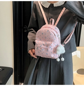 Gros plan d'un mini sac à dos rose à fleurs avec un charm nuage en peluche et fermetures