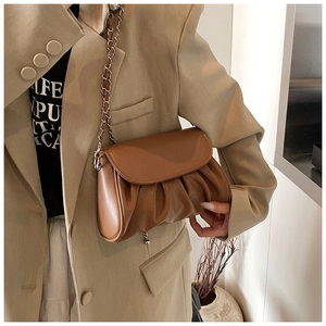 Close-up of caramel pleated shoulder bag with chain strap styled on a khaki suit